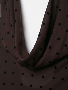 Detail of sheer brown chiffon fabric with black flocked polka dots and draped neckline
