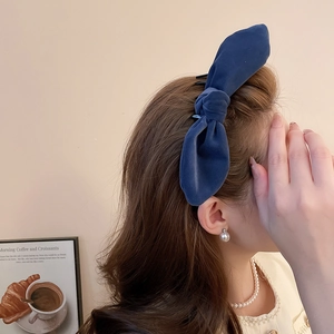 Detail of dark blue velvet bow hair clip worn by model with pearl jewelry accessories