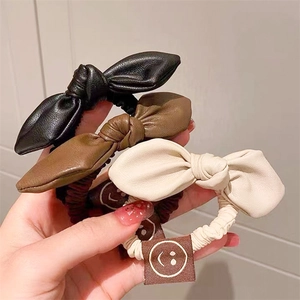 Set of 3 PU leather bow scrunchies in black, brown, and beige with smiley face tag