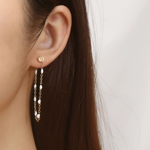 Detail of gold tassel chain earrings with pearls and zircon on a model