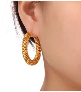 Macro shot of gold hoop earrings with intricate mesh texture and hollow honeycomb design