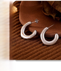 Macro shot of silver U-shaped horseshoe earrings on textured fabric background