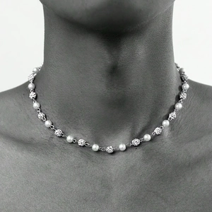 Detailed view of silver chain necklace with pearls and rhinestone beads worn by model