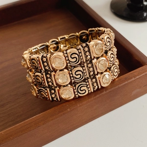 Detailed view of vintage gold multi-layer rhinestone bracelet on a brown wooden tray