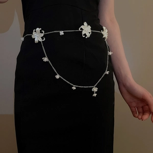 Detailed close-up of a silver chain belt featuring white acrylic flowers and pearls
