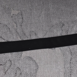 Close-up of gray camouflage cotton fabric texture and black woven strap detail on cap