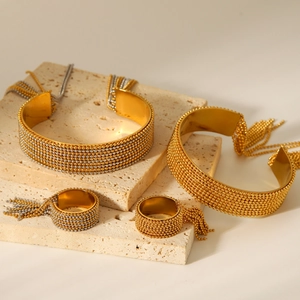 Detail of gold and silver beaded tassel bracelets and rings set on a stone surface