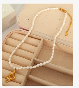 Detailed close-up of Baroque freshwater pearls with a golden snake pendant and chain