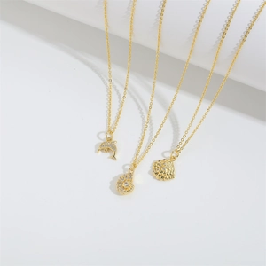 Three gold ocean-themed necklaces with dolphin, conch, and shell pendants with small zircons