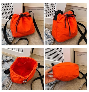 Detailed views of the bright orange drawstring bucket bag showing interior space and bottom