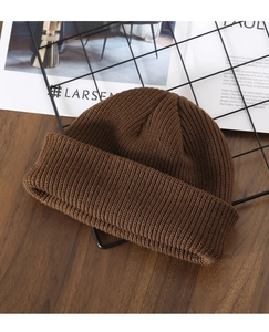 Detailed texture of dark brown knit beanie on a rustic wooden table with decor