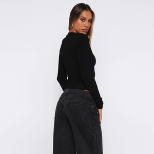 Detail view of women's black long sleeve fitted top and dark gray high waist wide leg jeans