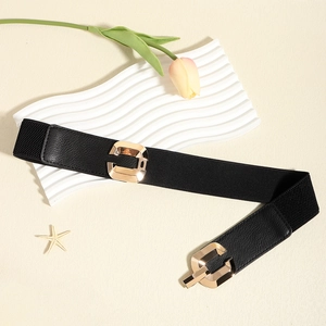 Detail of a black elastic waist belt with an interlocking gold geometric metal buckle