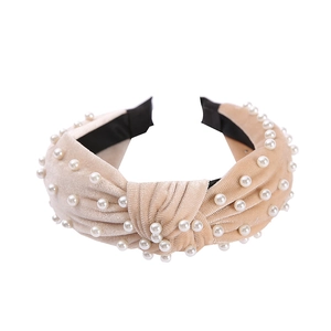 Close-up of beige velvet headband with pearl beads on a clean white background