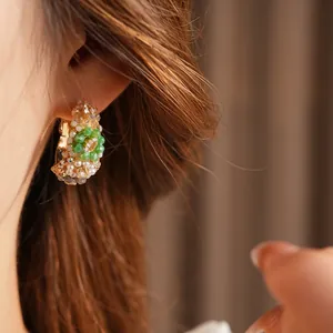 Vintage C-shaped woven earrings with green beads and pearls on model side view