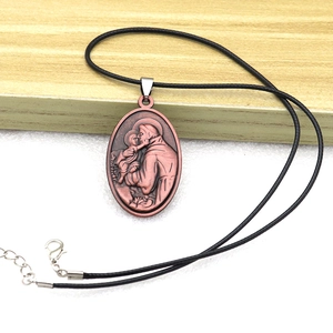 Detailed close-up of a bronze religious medallion featuring Saint Anthony on a black cord