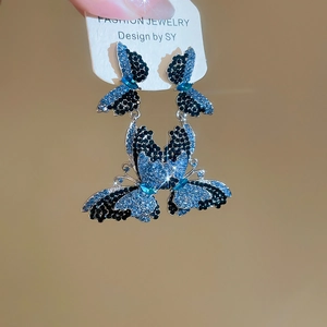 Detail view of shimmering blue and black butterfly earrings with sparkling crystals