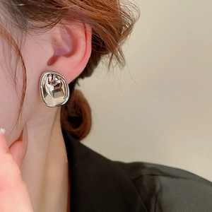 Close-up of a silver irregular geometric earring with a liquid metal effect on a model