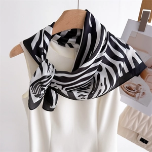 Fashionable zebra print silk scarf tied on white top against a minimalist studio background