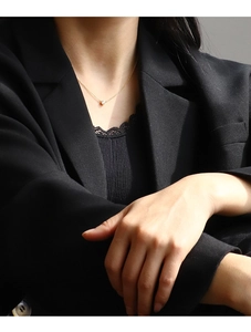 Detailed close-up of a minimalist gold necklace with a round zircon pendant on a model