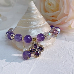 Macro detail of natural amethyst bracelet with zircon clover charm on a shell background