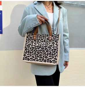 Close-up of linen tote bag with leopard print and brown handles on a street style model