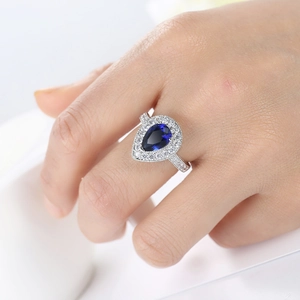 Elegant pear-cut royal blue sapphire ring with white cubic zirconia accents on silver band