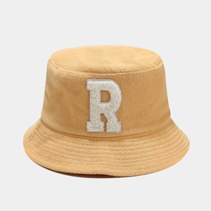 Detailed close-up of yellow bucket hat featuring soft bouclé fabric and large white letter R