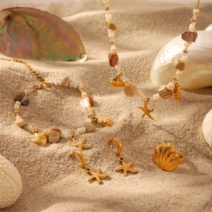 Golden starfish and seashell jewelry set including necklace, bracelet and earrings on sand