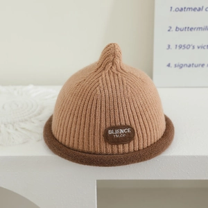 Detailed knit texture of a brown baby pointy hat with a rolled brim and leather logo