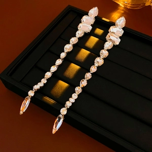 Macro shot of silver needle crystal drop earrings with sparkling rhinestones on black tray