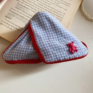 Detailed view of blue plaid fabric hair claw with pink bear ornament and red trim piping