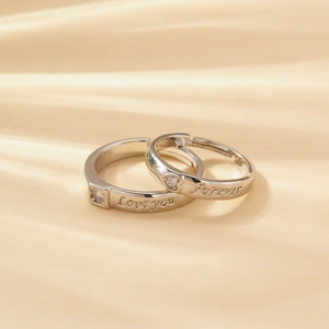 Detail of adjustable couple rings with Love you and Forever engravings on satin
