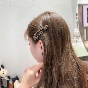 Leopard print oval hollow hair clip shown worn on a model's hair from a side view