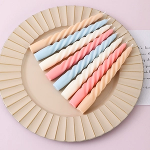 Close-up of colorful spiral taper candles in a beige ceramic tray for home decor