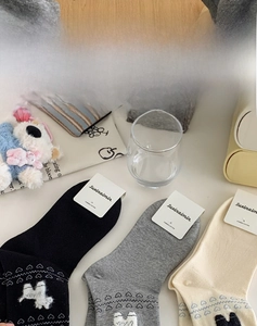 Detail showing combed cotton socks with animal embroidery and heart patterns on table