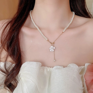 Close-up of pearl camellia pendant necklace showing elegant drape on woman neck