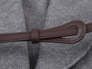 Detail view of grey knit fabric with a brown leather belt and fine stitching accents