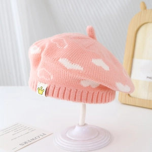 Detail of pink knitted beret featuring white clouds and a soft ribbed elastic band