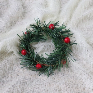 Mini Christmas wreath with red berries and green pine needles on white plush background