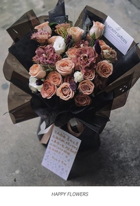 Close-up of vintage roses and lisianthus in dark premium wrap with a greeting card