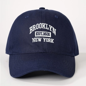 Close-up of white Brooklyn New York embroidery on a navy cotton baseball cap detail