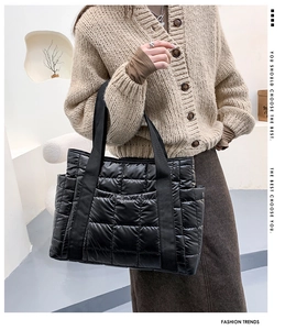 Detail of a black quilted tote bag with side pockets and a padded puffer nylon texture