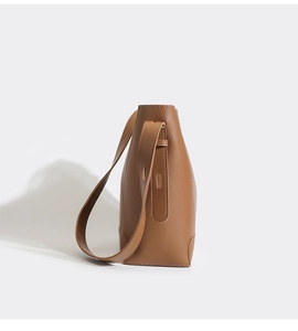 Close-up of brown leather bucket bag with adjustable wide shoulder strap and smooth finish
