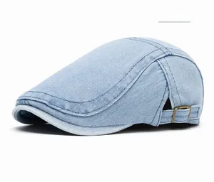 Detail of light blue washed denim newsboy cap with adjustable bronze metal buckle