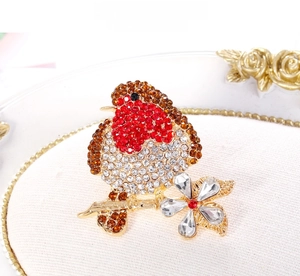 Macro detail of a bird brooch with red rhinestones on a golden flower branch