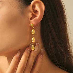 Three-tier gold teardrop earrings in polished 18k plated finish on a fashion model