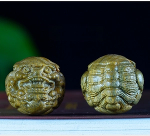 Detailed close-up of pair of hand-carved sandalwood PiXiu wooden sphere beads