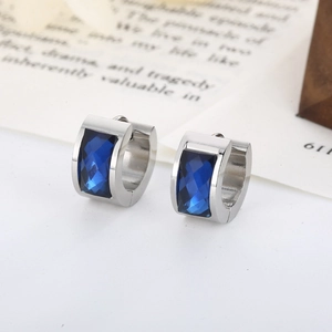 Detailed close-up of silver steel hoop earrings with faceted deep blue zircons