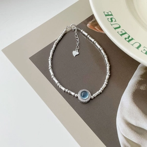 Detail of S925 silver bamboo-style bracelet with blue gemstone and heart charm